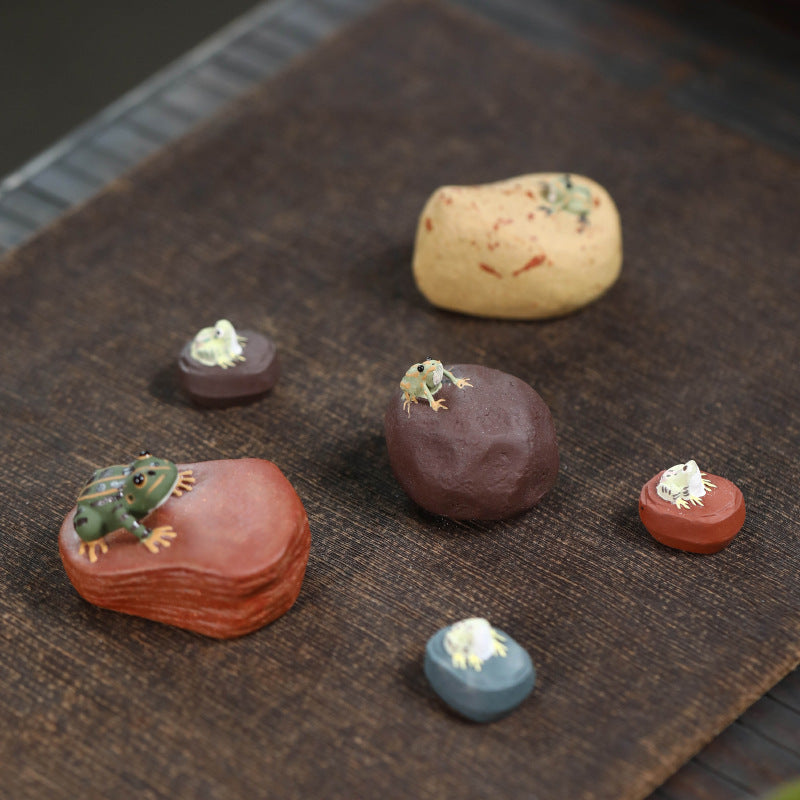 A handcrafted, creative and personalized tea set accessory made of Yixing purple clay, featuring a ceramic tea pet and a water-spraying frog stone figurine