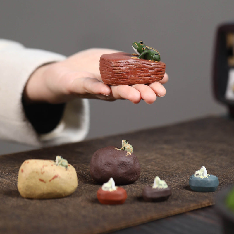 A handcrafted, creative and personalized tea set accessory made of Yixing purple clay, featuring a ceramic tea pet and a water-spraying frog stone figurine